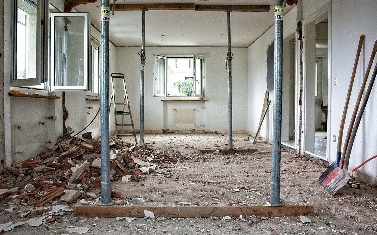Departamento en obra con escombro, puntales metálicos y herramientas antes de la limpieza fina
