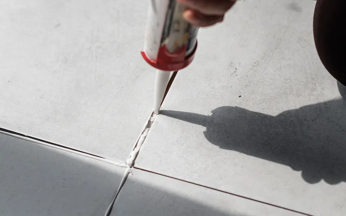 Aplicación de sellador en las juntas de un piso de porcelanato claro